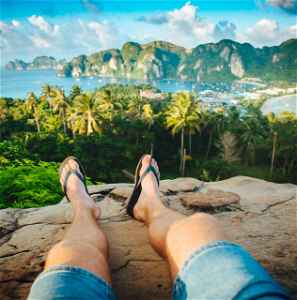 Traveller sitting on a rock overlooking jungle, ocean and surrounding islands
