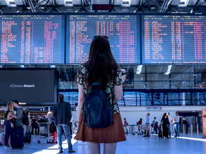 Person looking up at a departures board in an airport