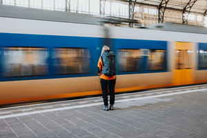 Backpacker at train station as train goes past 