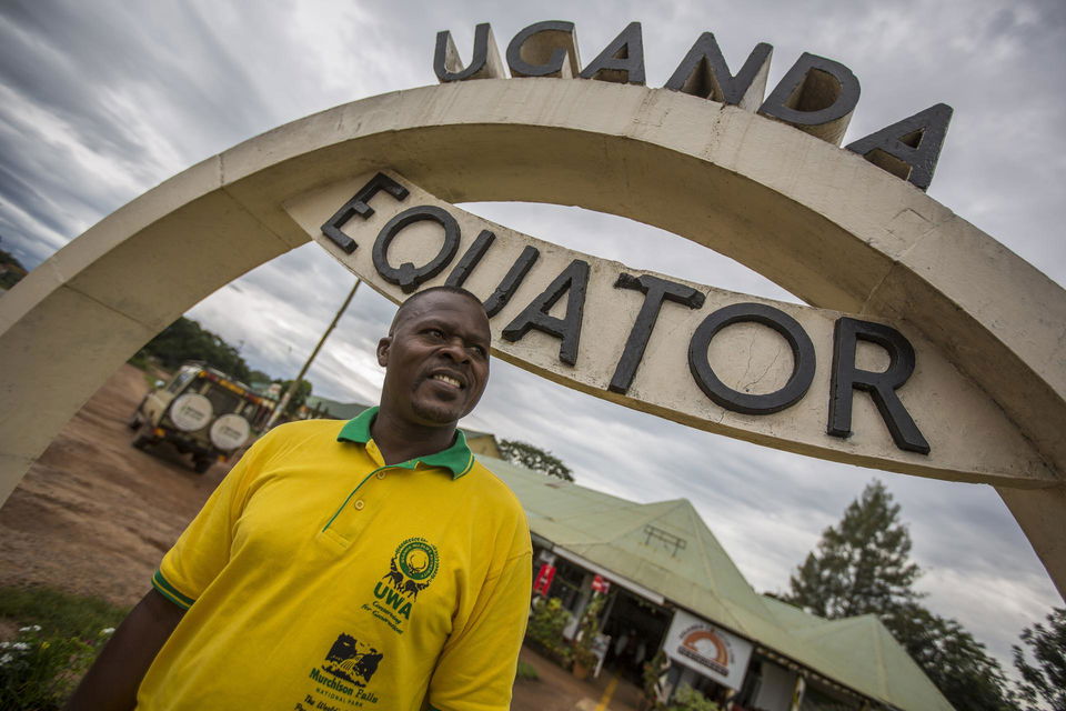 Man standing next to Uganda Equator stop
