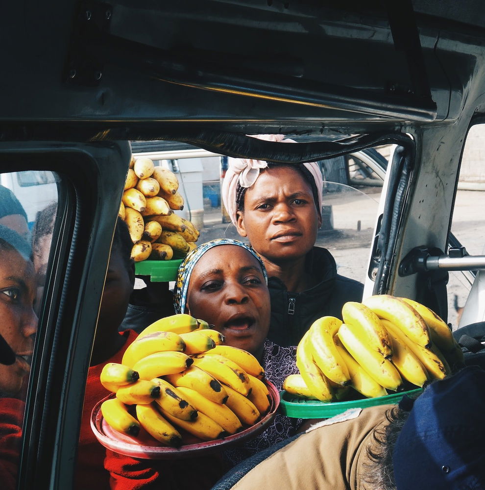 Street vendors trying to sell bananas to people in a vehicle in Tanzania