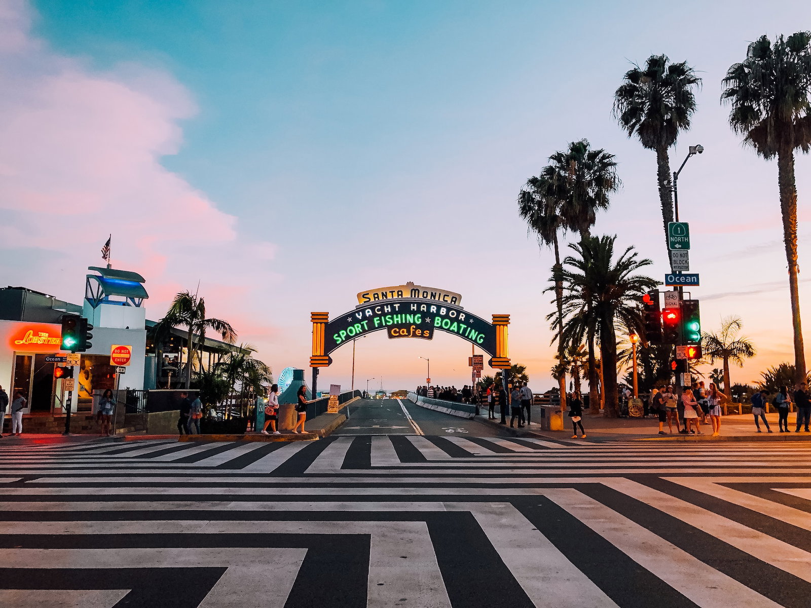 A street crossing and archway with the words 'Santa Monica' at sunset
