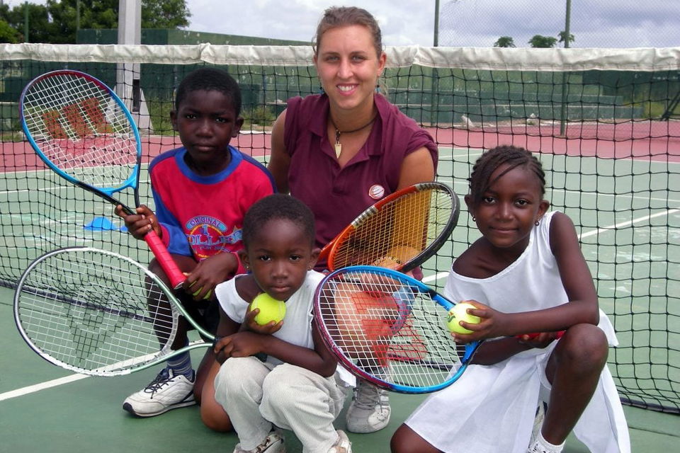 Volunteer with children in ghana coaching tennis