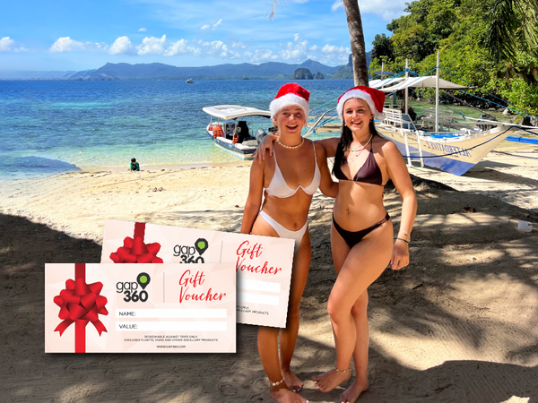 Two travellers on beach in the Philippines wearing Santa hats