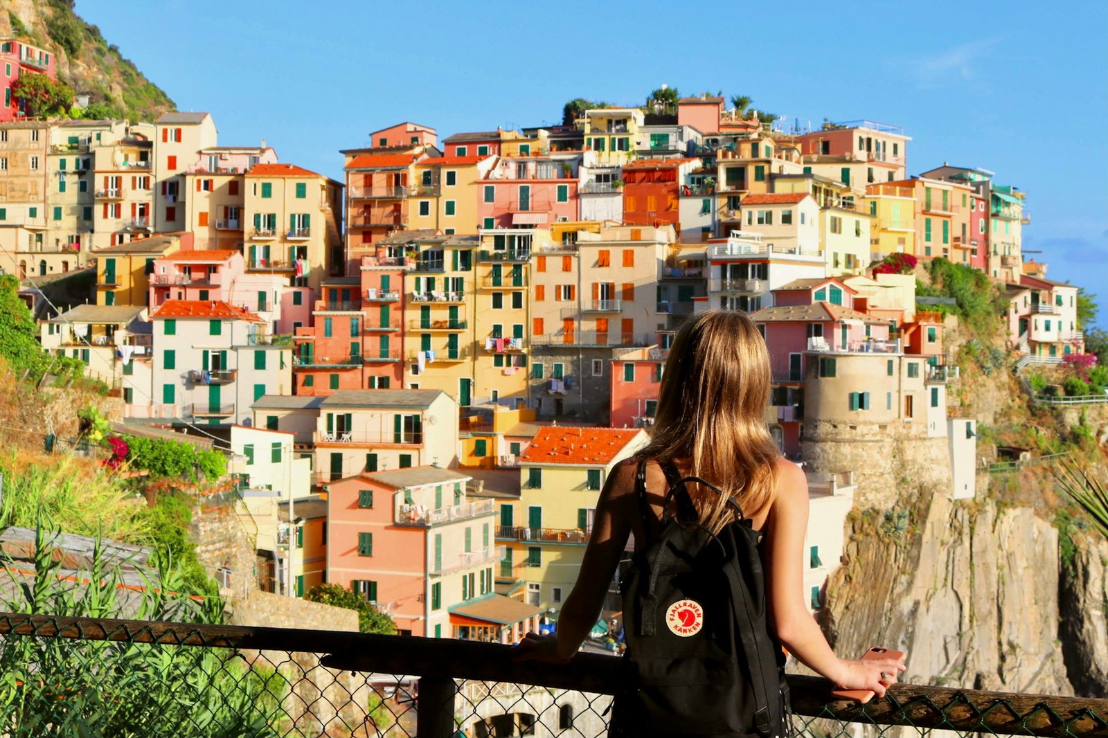 Girl looking out to rainbow coloured fishing houses on stacked cliffs