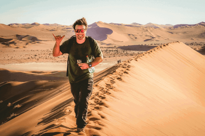 Group traveller walking through sand dunes in Africa