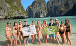 Group travellers holding Gap 360 flag in Maya Bay Koh Phi Phi Thailand