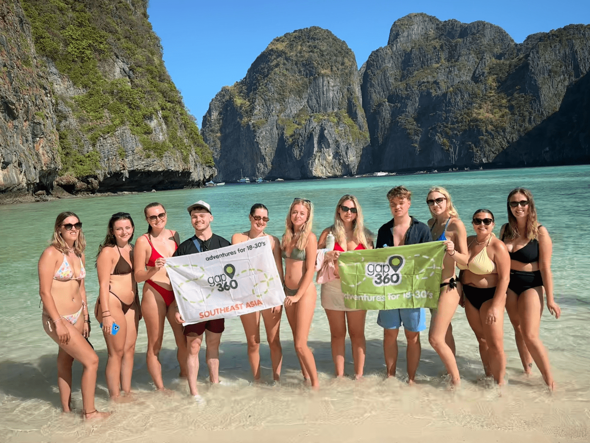 Group travellers holding Gap 360 flag in Maya Bay Koh Phi Phi Thailand