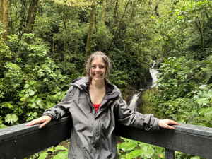 Woman in front of small waterfall in a cloud forest with lots of green trees, Monteverde Cloud Forest, Costa Rica