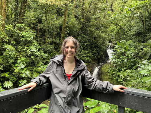 Woman in front of small waterfall in a cloud forest with lots of green trees, Monteverde Cloud Forest, Costa Rica