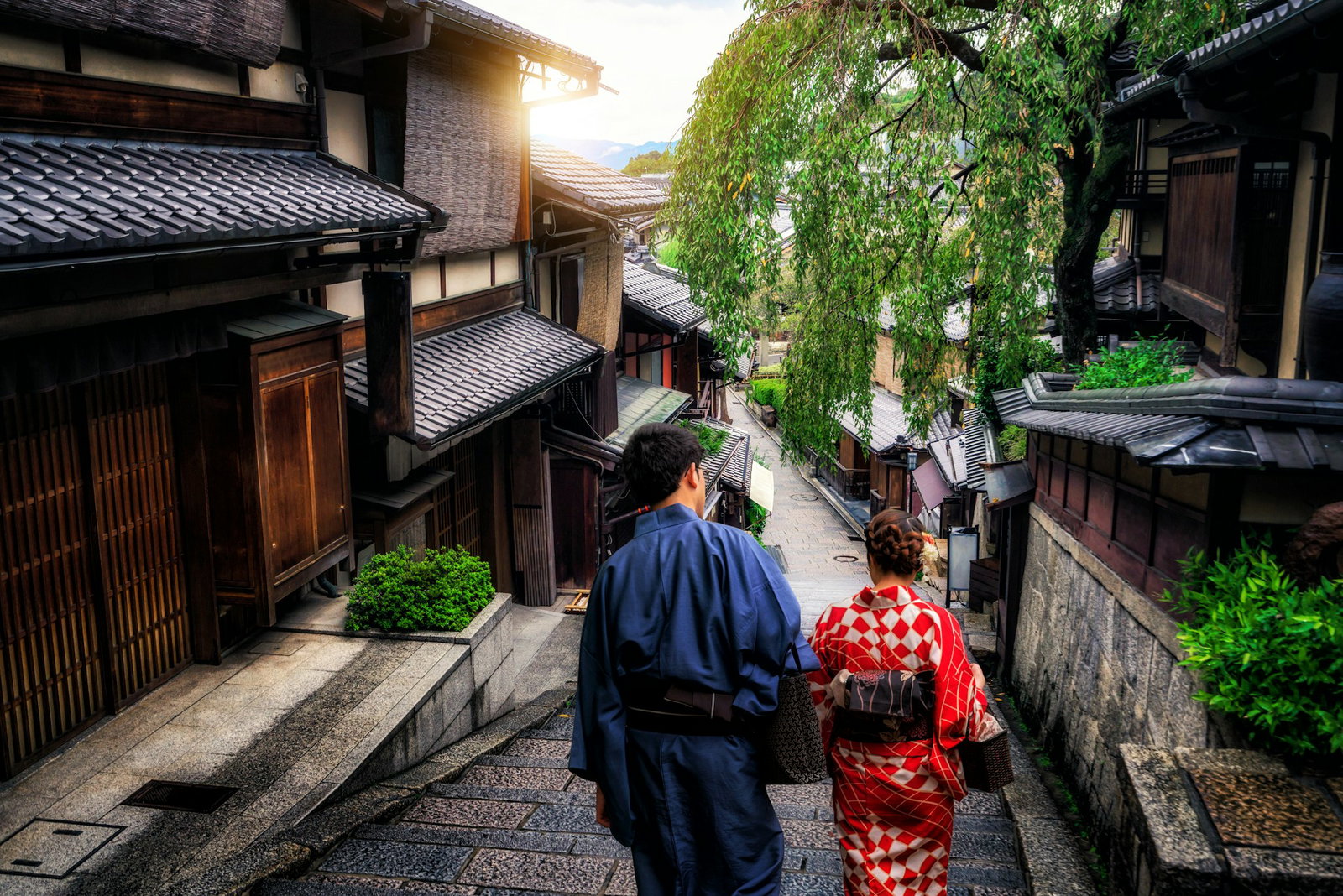 Man and woman in traditional kimonos walking in village with wooden homes, Kyoto