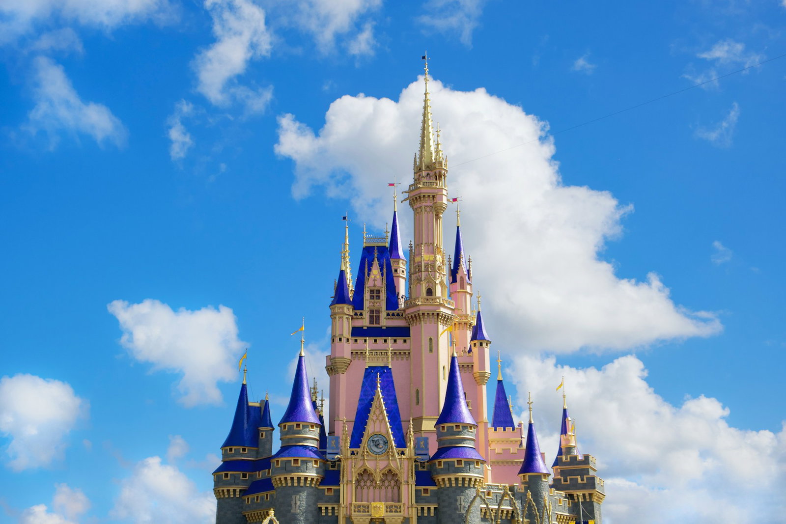Bright blue sky with bright pink palace with purple, grey and gold accents in the centre, Disneyworld