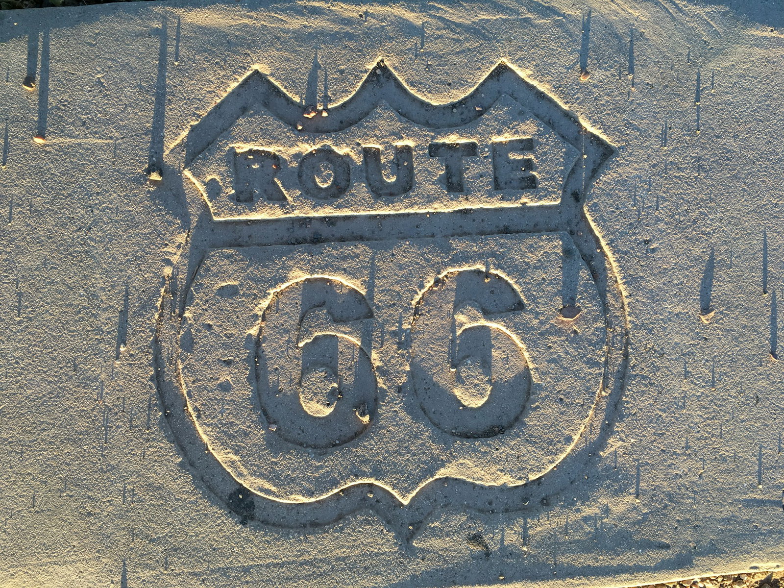 Route 66 in police badge marked into sandy ground