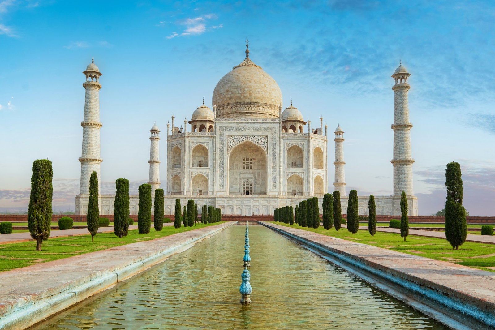 Narrow fountain with bushes leading to huge white domed temple and towers, Taj Mahal