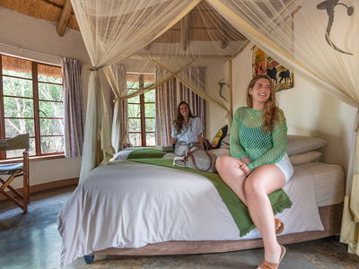 Female travellers sat on bed at hlane national park accommodation