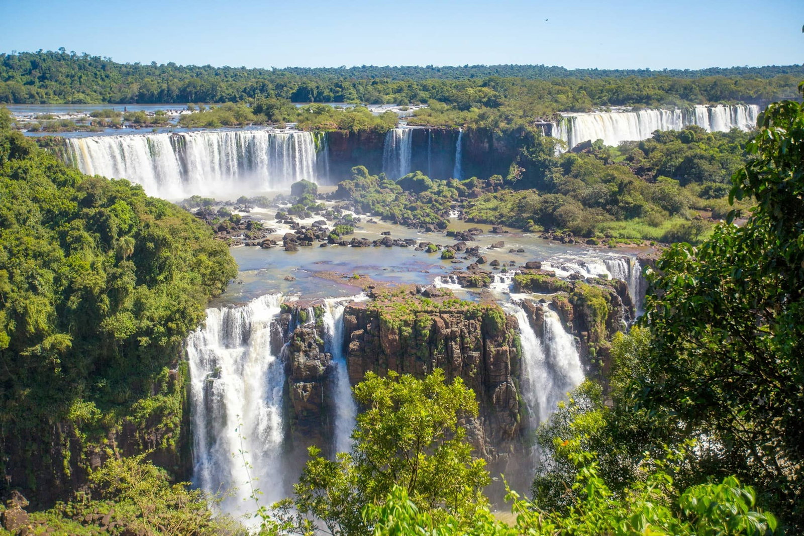 Viewpoint surrounded by jungle and cascading waterfalls with rocks on clear day