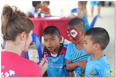 Kids standing with and listening to a volunteer teacher