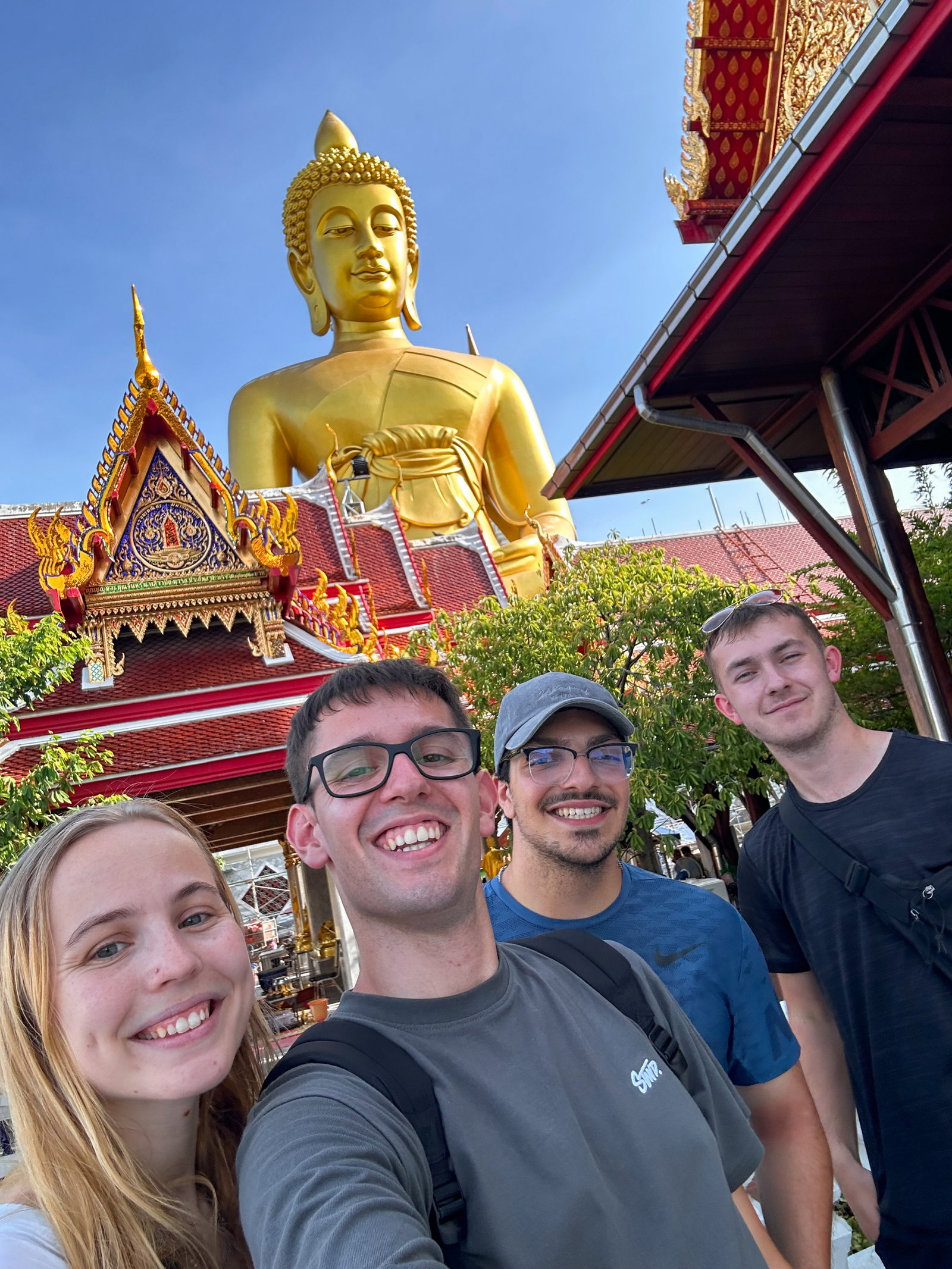 Travellers posing in front of golden Buddha