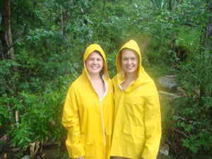 Travellers in raincoats standing in front of dense vegetation
