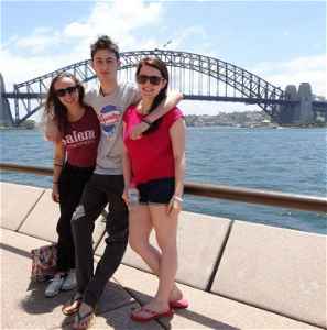 Three travellers standing in front of the Sydney Harbour Bridge and surrounding harbour