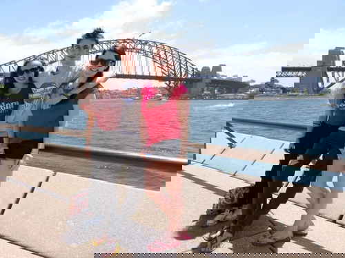 Three travellers standing in front of the Sydney Harbour Bridge and surrounding harbour