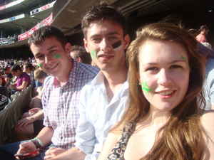 Travellers sitting in the stands at a cricket match