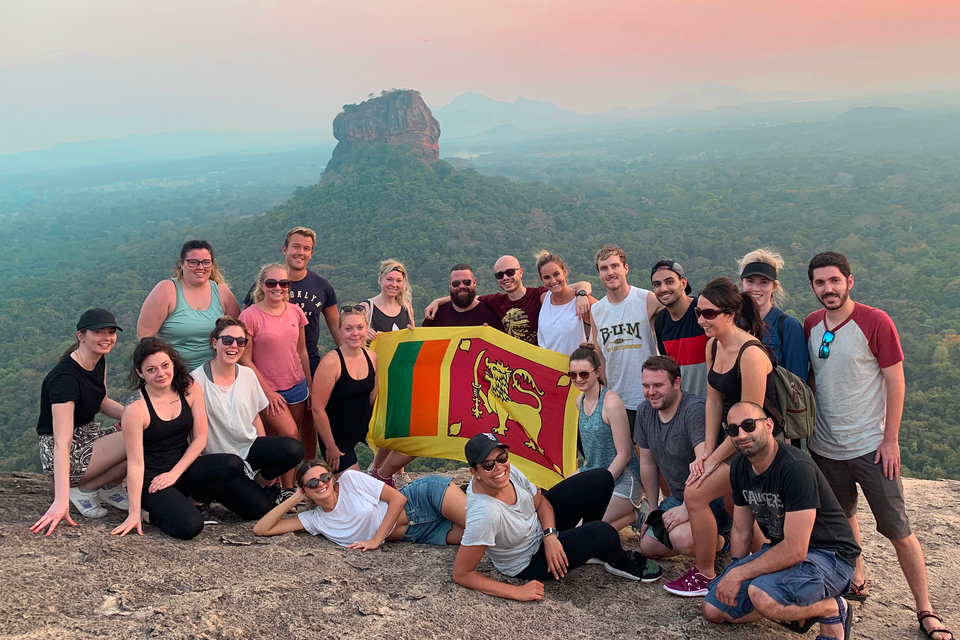 Group of travellers with Sri Lankan flag in front of Sigiriya rock