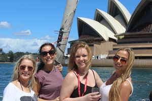A group of travellers on a boat in front of the Sydney Opera House