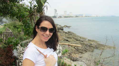 Jane standing near the edge of the water with a city visible in the distance