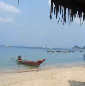 Boats on the shore of a beach with huts in Koh Tao, Thailand