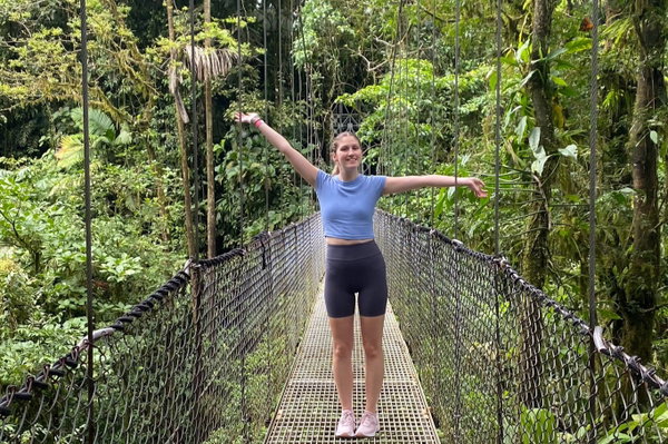 Traveller on suspension bridge in green rainforest with lots of trees, Costa Rica