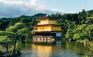 Floating golden traditional temple on pond surrounded by dark forest on a cloudy day