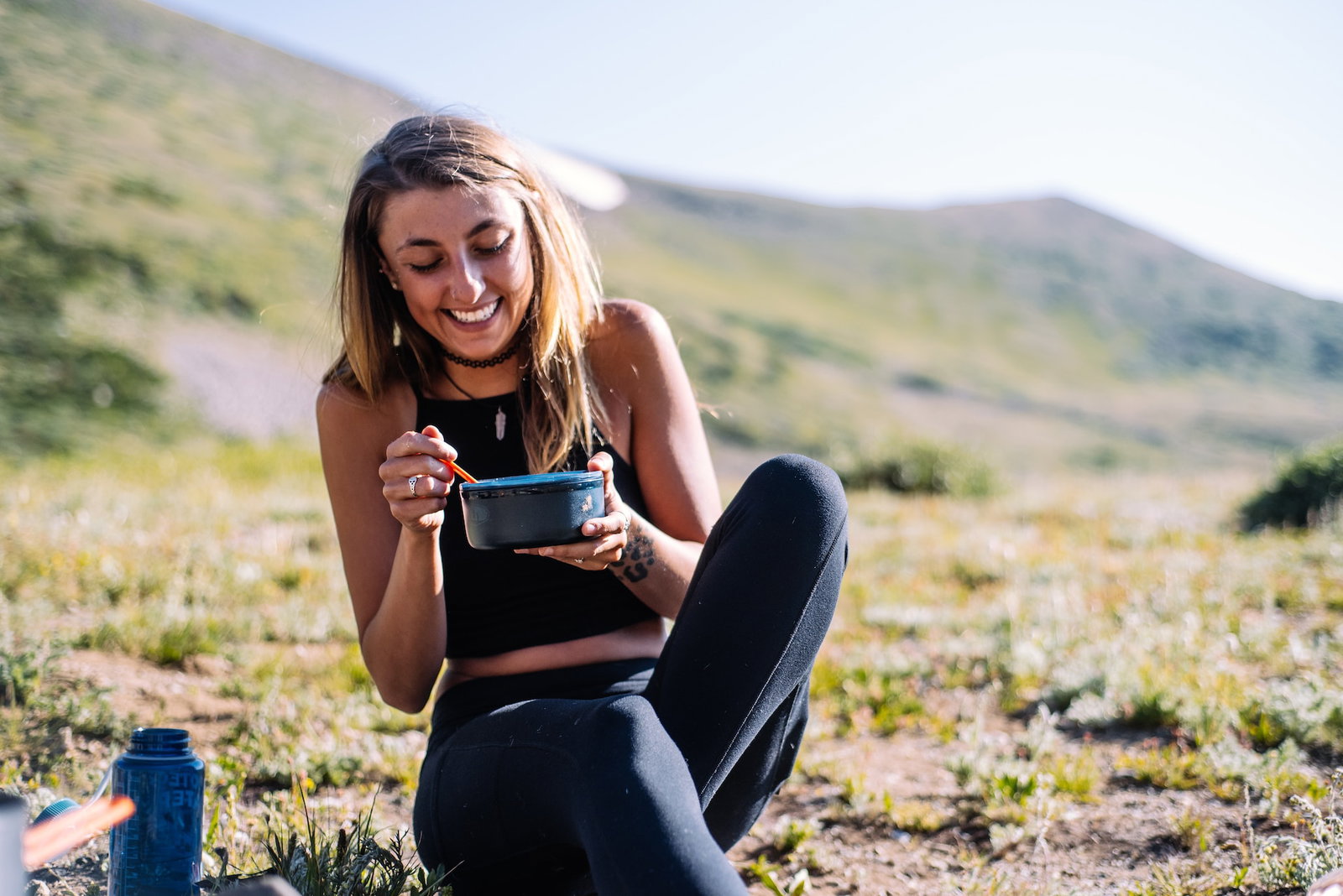 A traveller sitting at the foot of a mountain smiling and eating