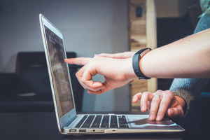 Hand pointing to a laptop screen