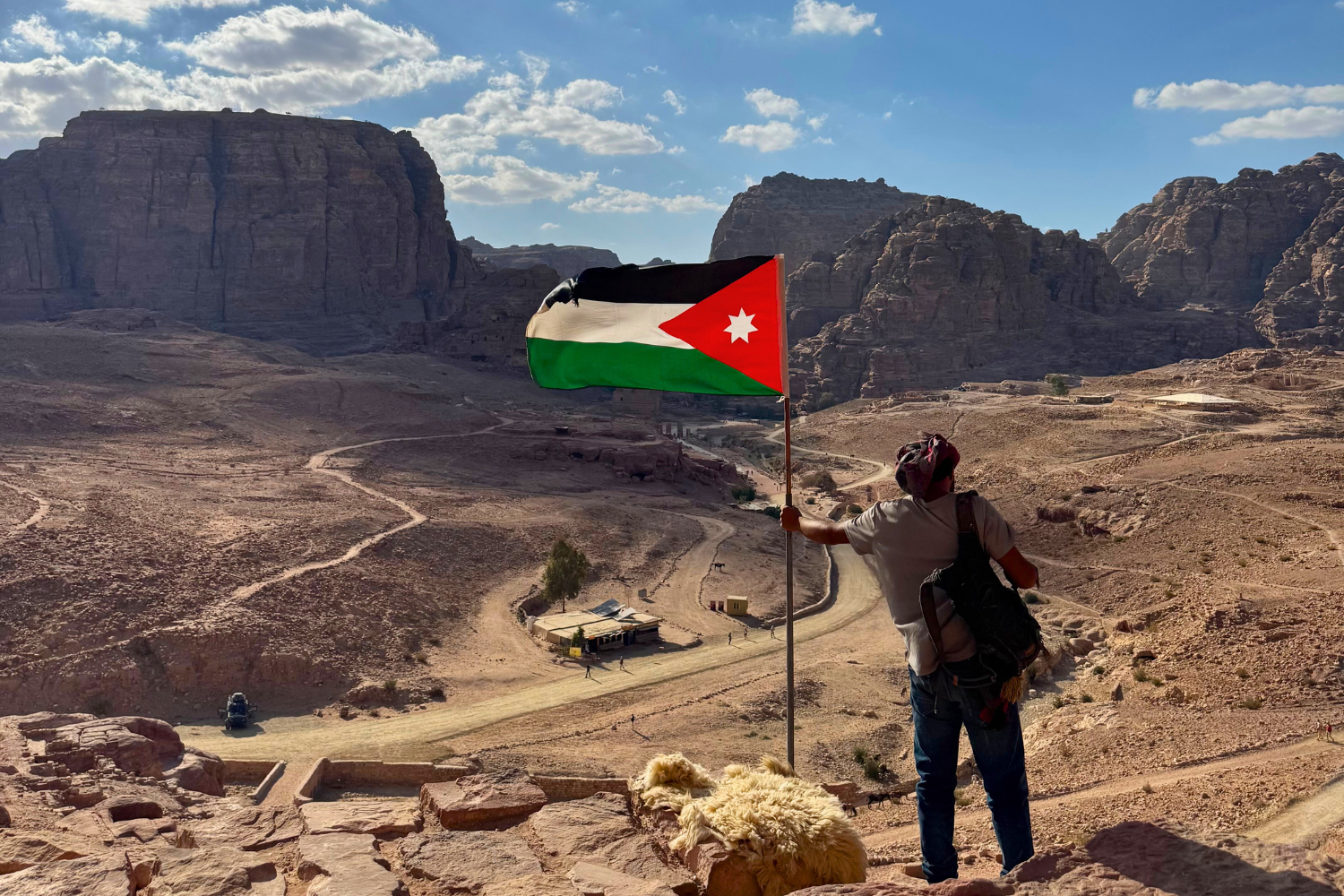 Local man holding up Jordanian flag overlooking landscape of Jordan