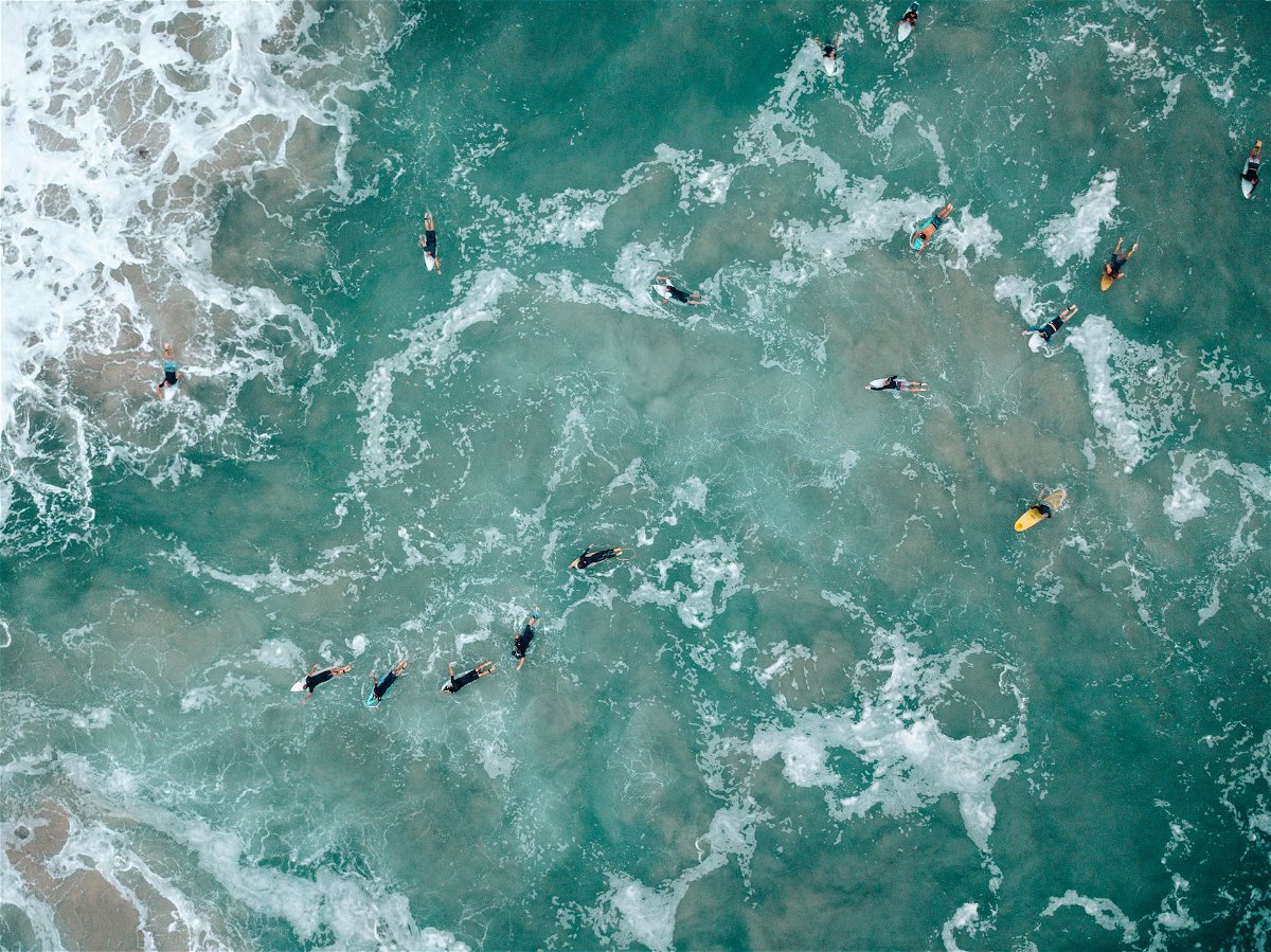 Top-down view of surfers paddling on foamy blue green water
