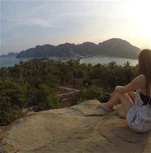 A travellers sits on a rock overlooking Koh Phi Phi island and surroundings