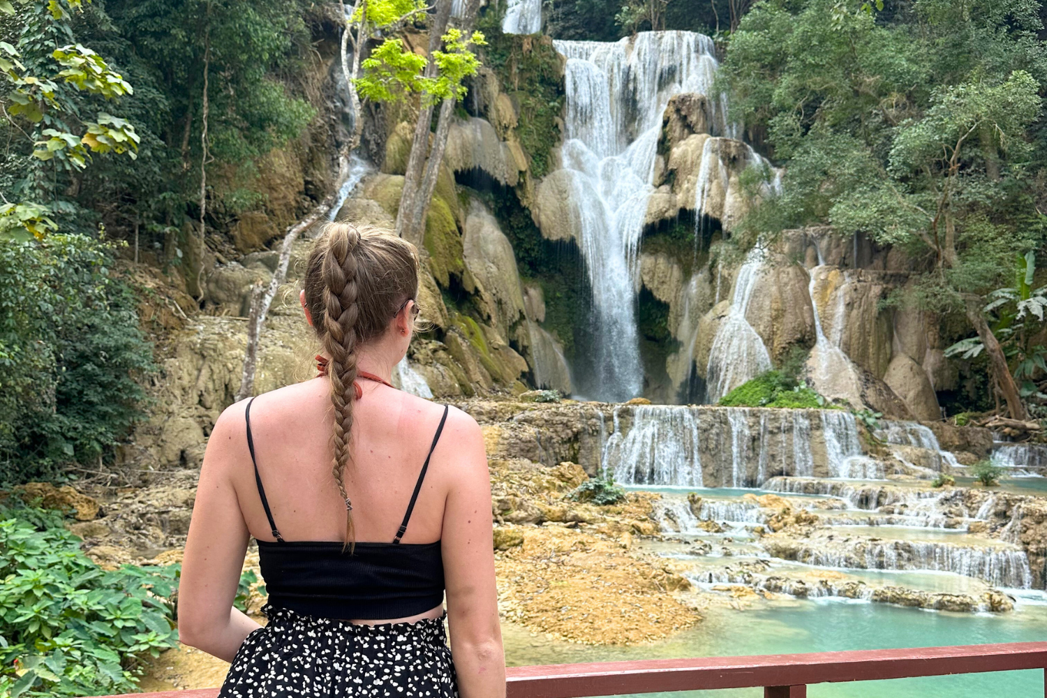 Traveller looking across to the milky blue waters of Kuang Si Falls in Laos