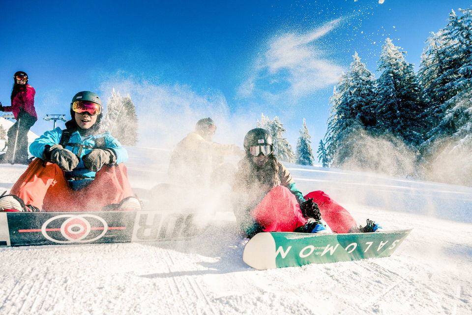 Snowboarders sat on piste