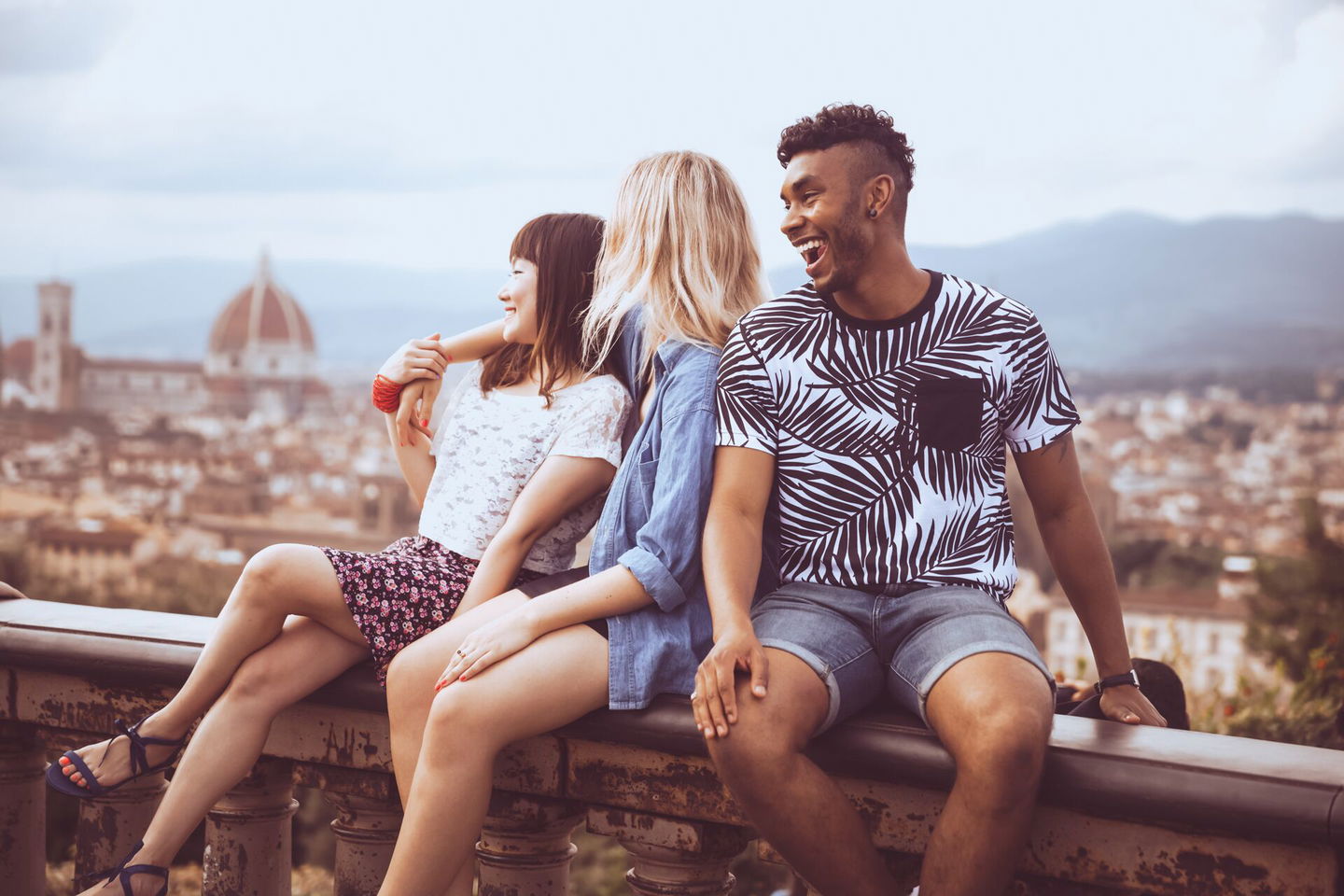 3 travellers sitting on the edge of a viewpoint in Florence, Italy
