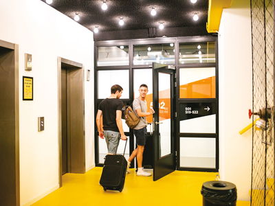2 travellers with luggage outside a lift in hostel
