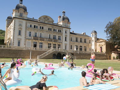 Travellers in chateau in pool with inflatables in France
