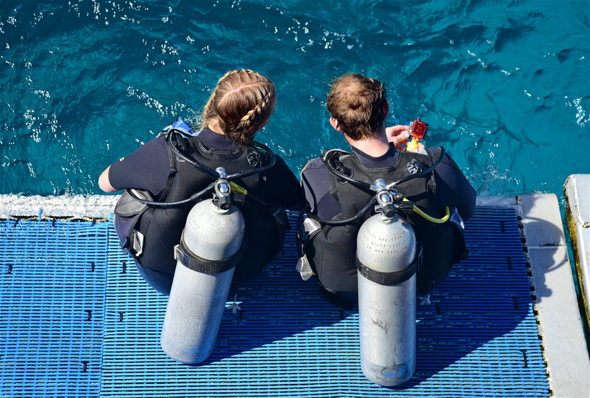 Two people sat before scuba diving the Great Barrier Reef, Australia