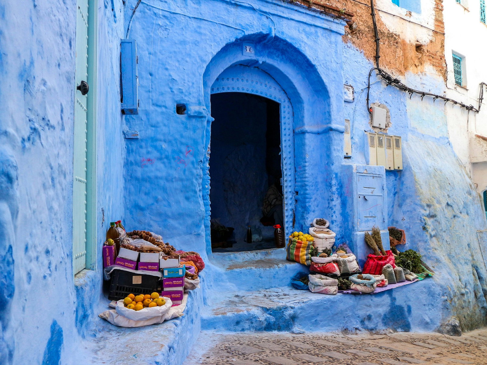 Little market selling fruits and vegetables outside bright blue building