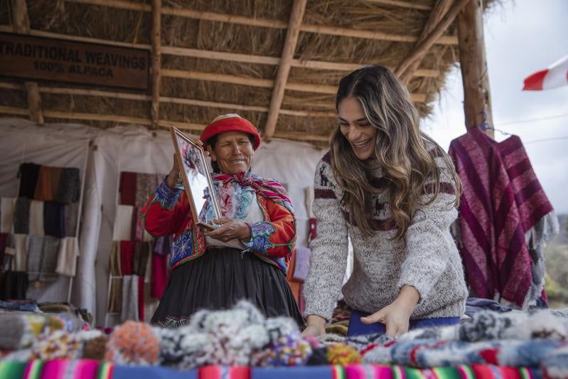 Lady showing another lady a mirror whilst looking at fabrics