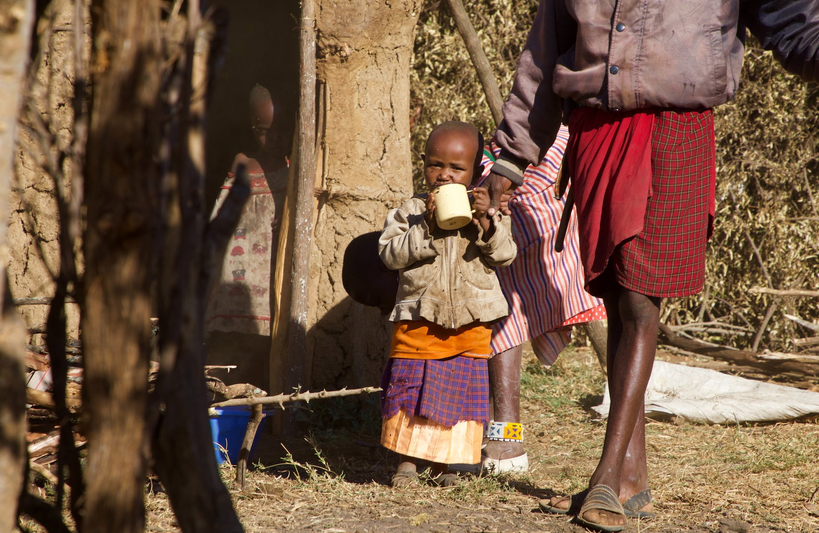 A young girl beside an adult drinking from a mug