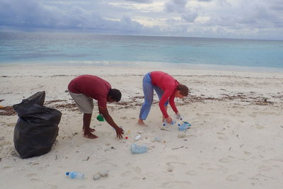 Two volunteers picking up rubbish on a beach