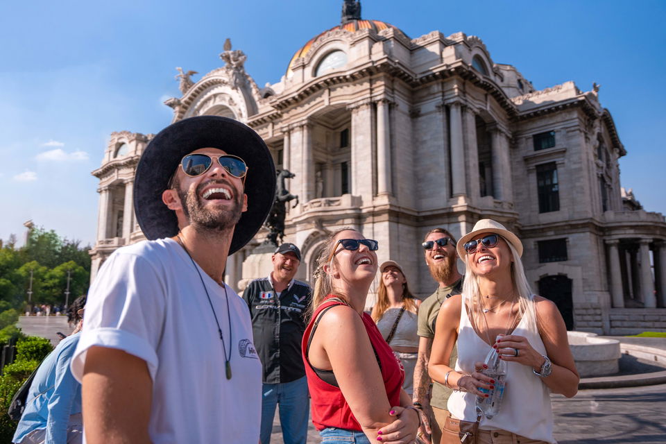 Smiling travllers in the sun outside building in Mexico City
