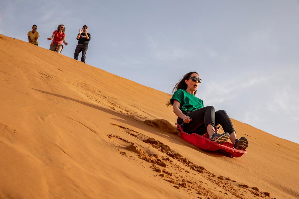 People sandboarding on sand dune in Merzouga desert Morocco