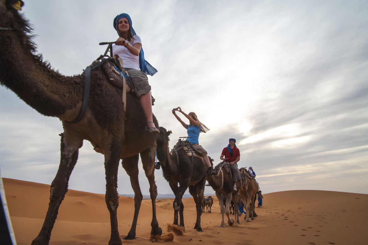 Three people riding camels in the desert